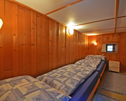 Schlafzimmer 2 – 2 Bett Schlafzimmer mit Kleiderkasten und Nachttischbeleuchtung.